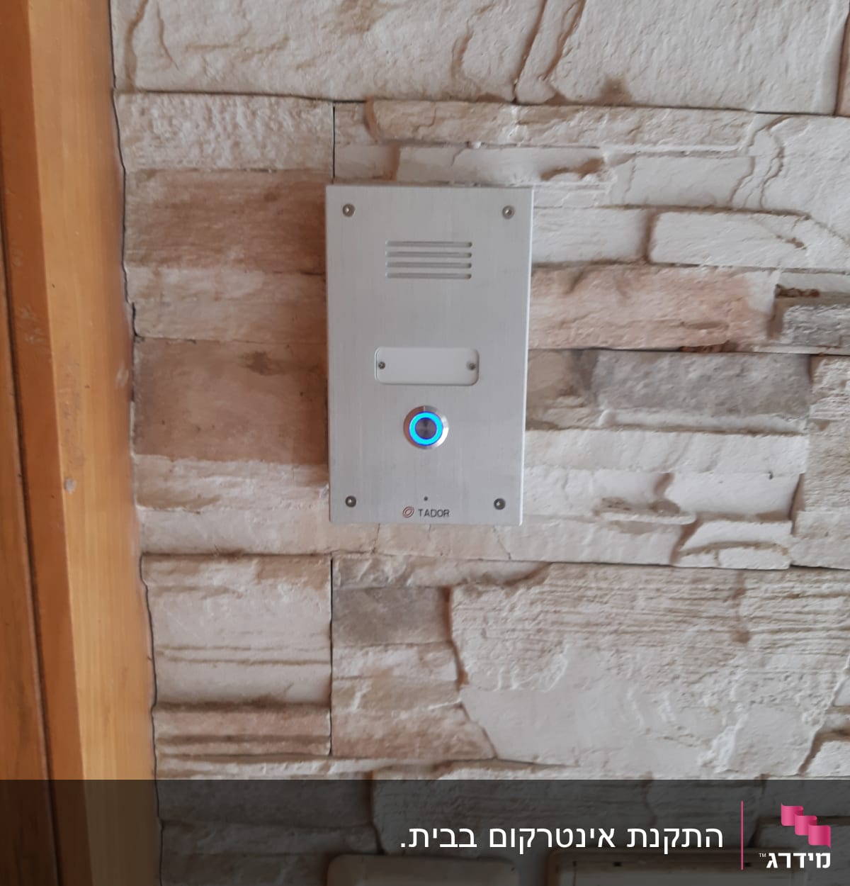 אינטרקום מותקן על קיר אבן עם כפתור מואר